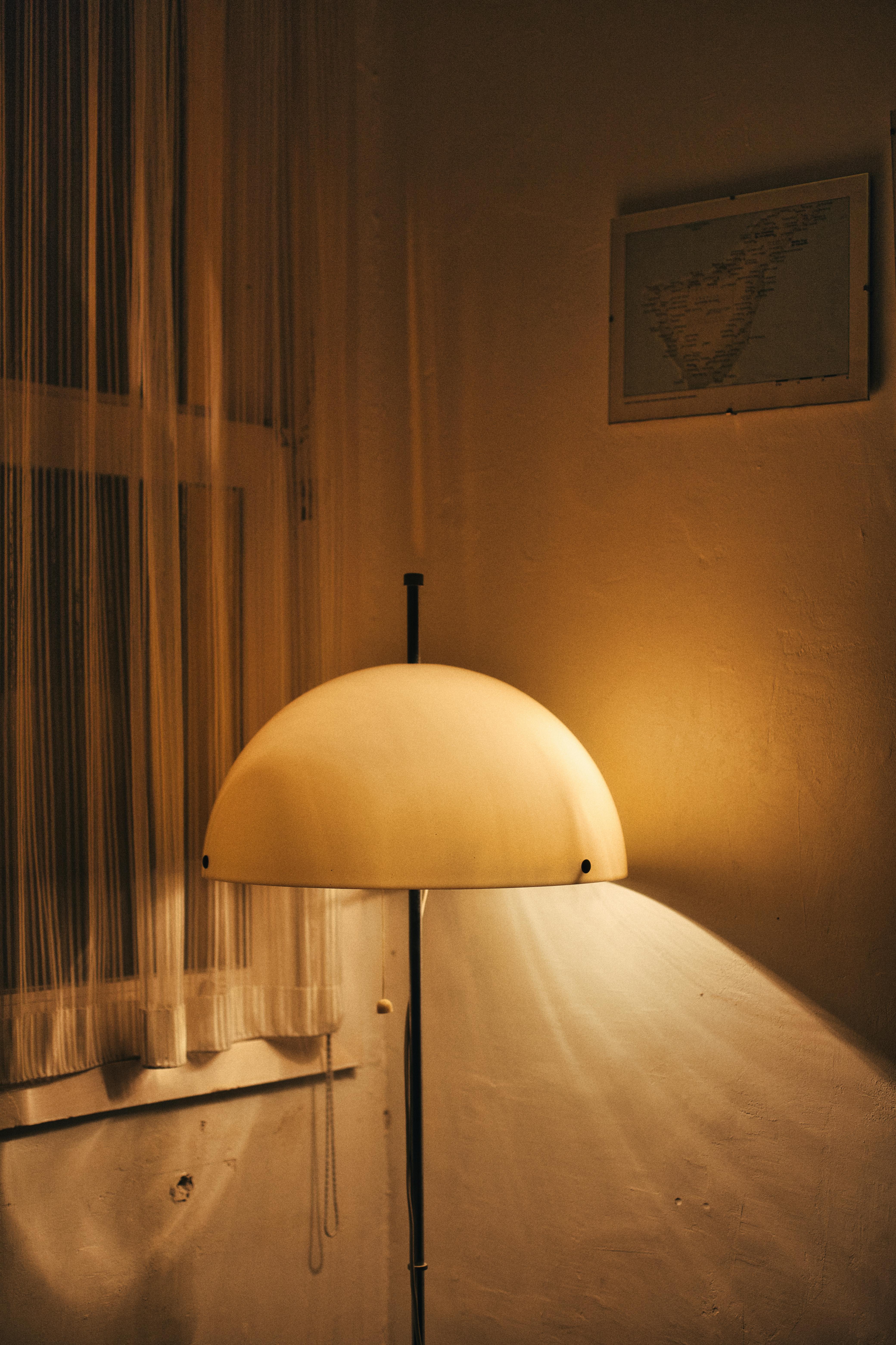 Free Warm lamp light against beige walls, creating a serene indoor ambiance. Ideal for cozy interior themes. Stock Photo