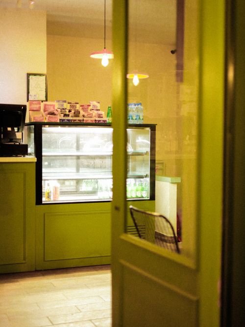 Free Warm and inviting café scene showcasing a counter and display fridge through an open door. Stock Photo