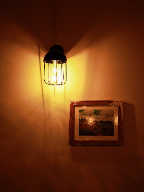 A light fixture hanging from the wall with a picture on it