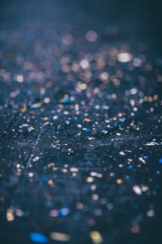 一张抽象图像中，彩色闪光和五彩纸屑散布在具有散景效果的黑暗表面上