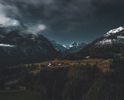 A peaceful mountain village nestled in a valley under a starry night sky.