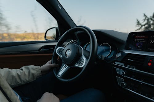 A man driving a car with his hands on the steering wheel