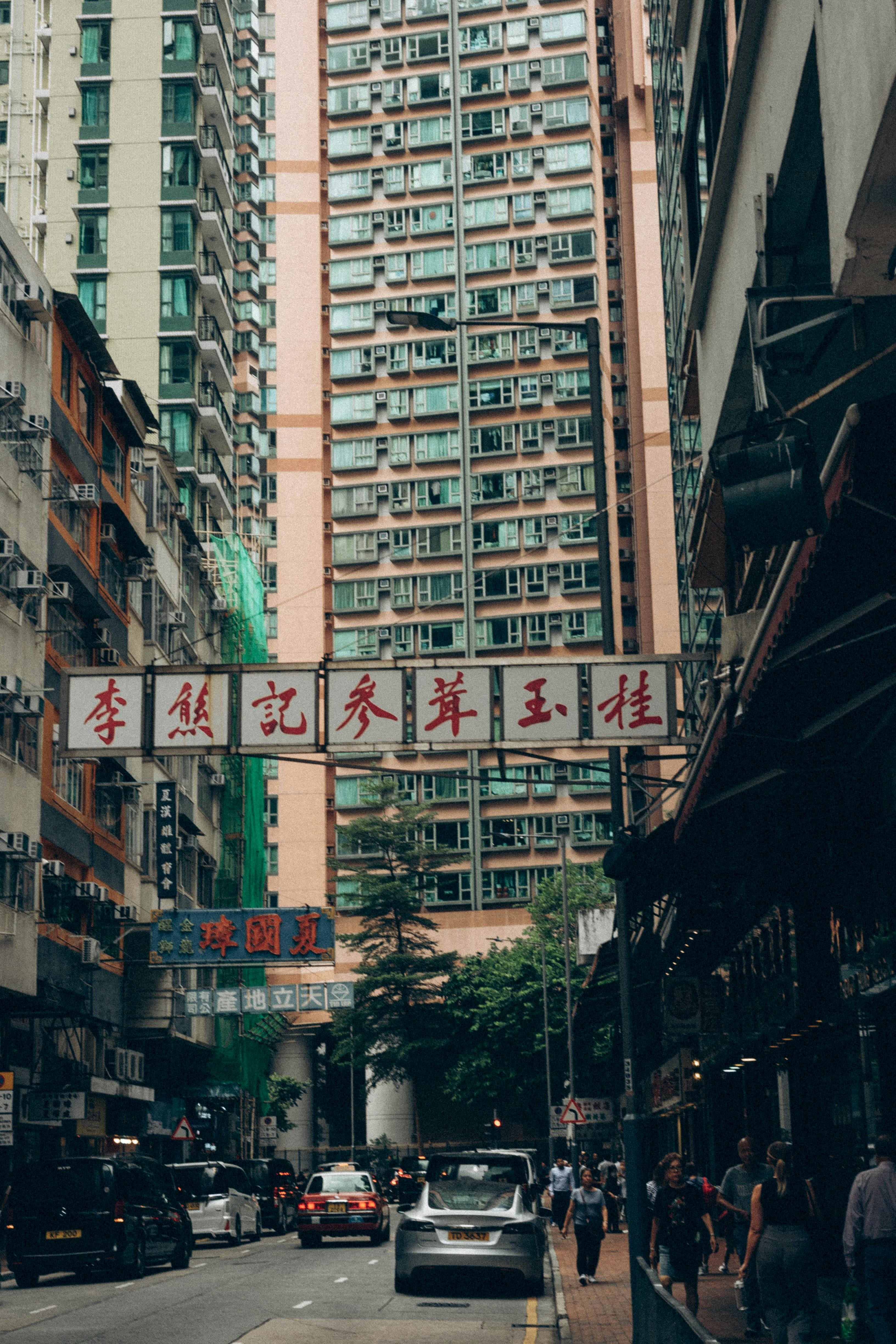 Urban street scene in Hong Kong featuring tall residential buildings and busy traffic.