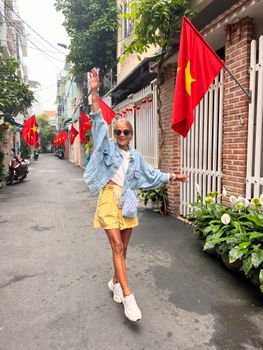 Smiling woman in urban Vietnam displaying fashion style on a lively city street.