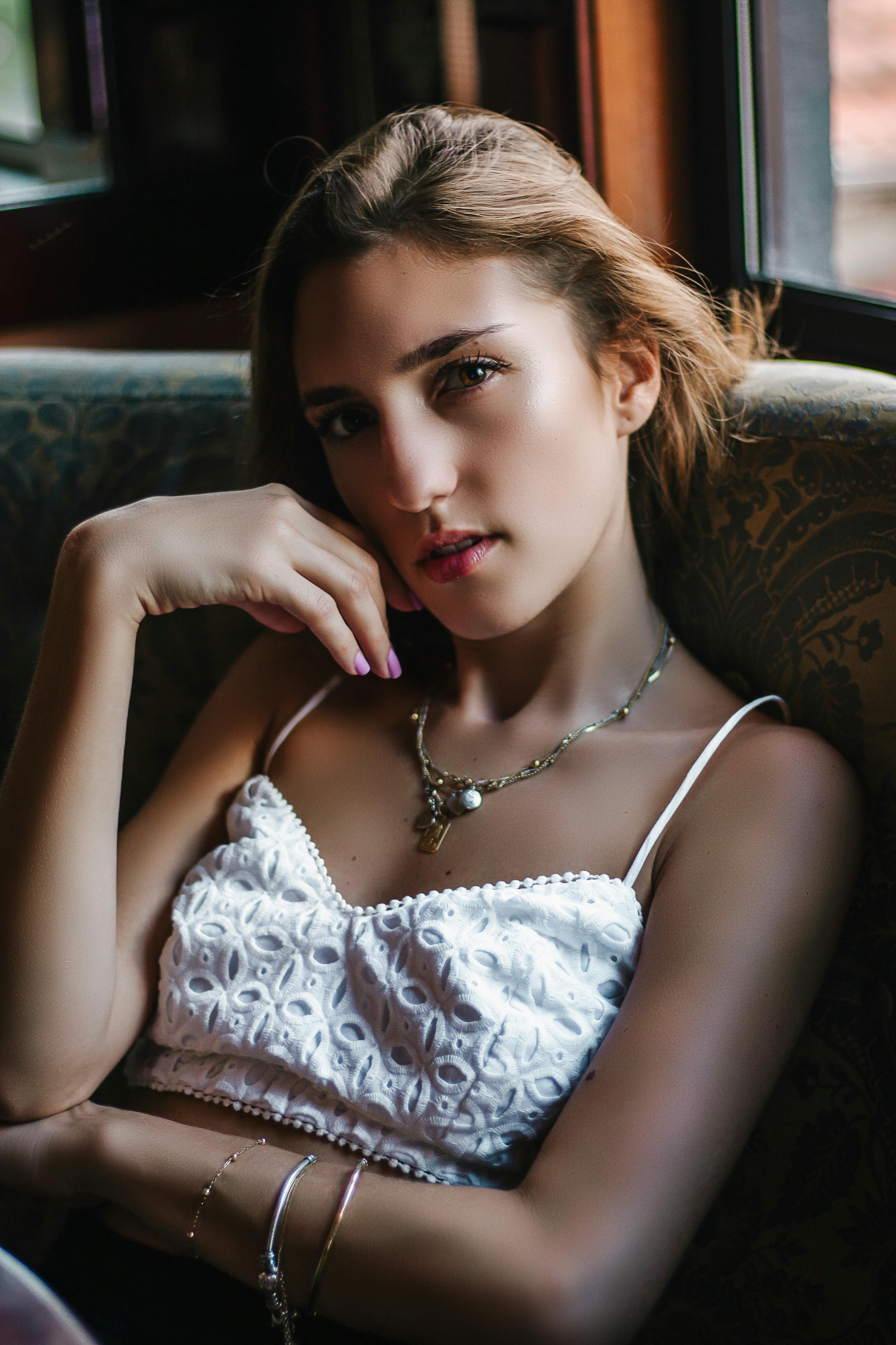 Stylish woman in a white crop top posing indoors, exuding elegance and fashion.