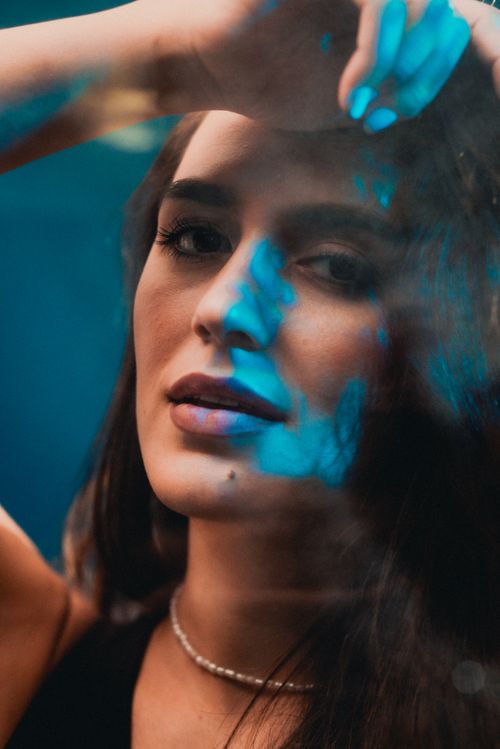 Free Stunning close-up portrait of a woman with a dramatic blue light effect, creating a captivating and artistic look. Stock Photo