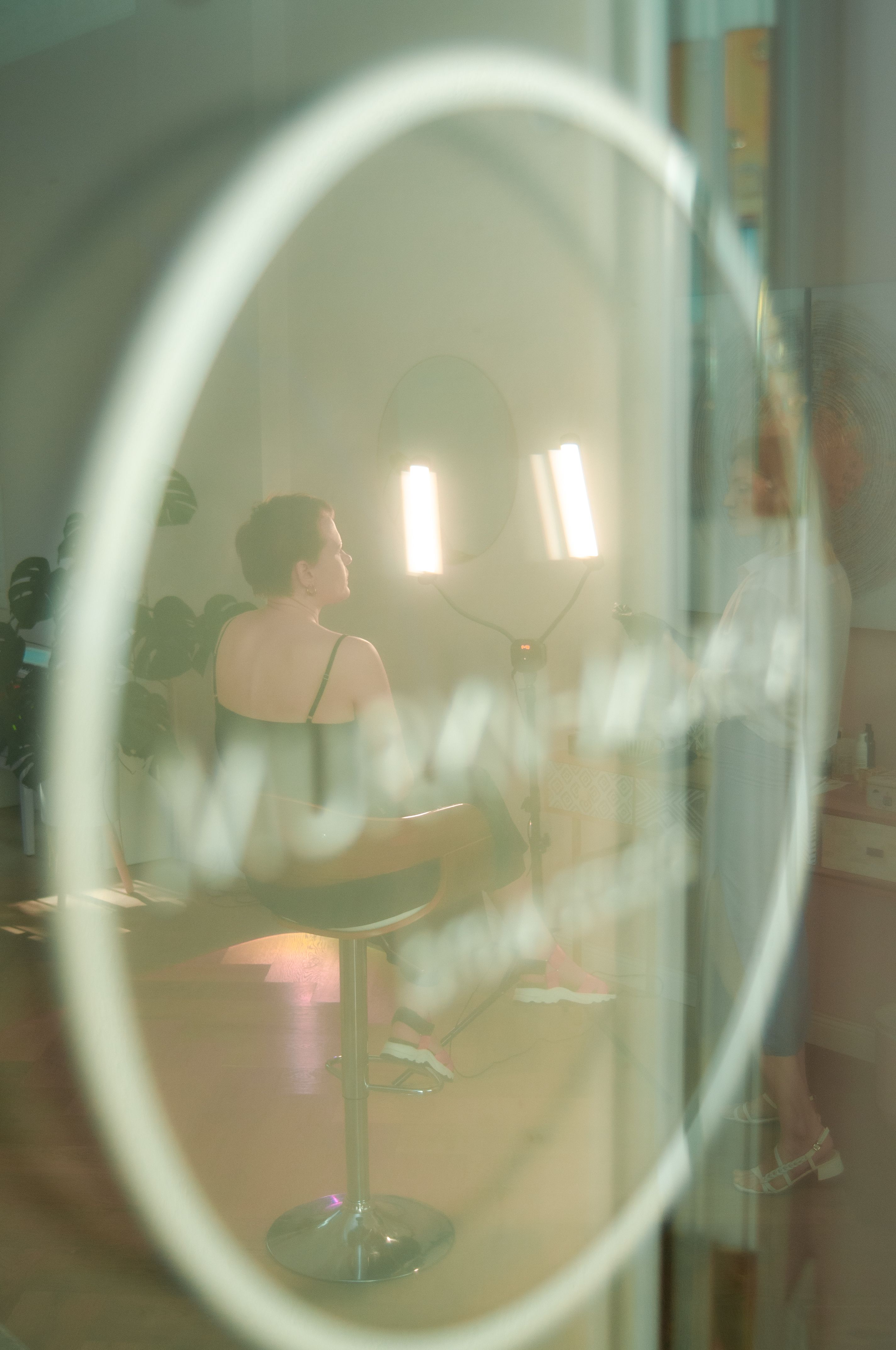 Creative photo shoot featuring model with blurred reflections and soft lighting.