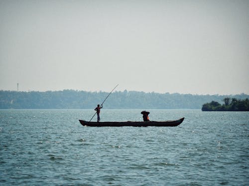 A man is fishing in a small boat on the water
