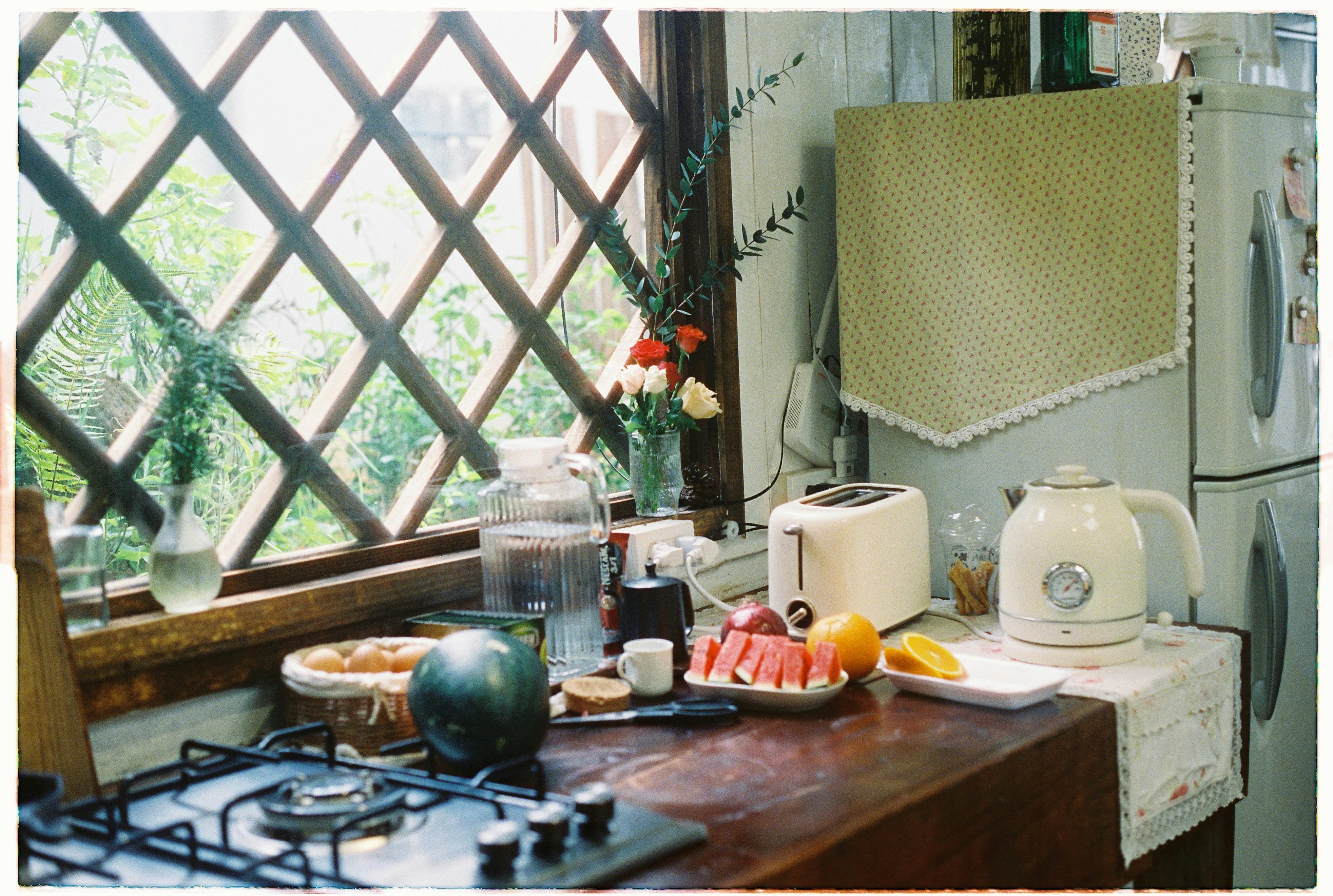 A sunny kitchen with toaster, kettle, and fresh fruit by a window, exuding a cozy and inviting atmosphere.