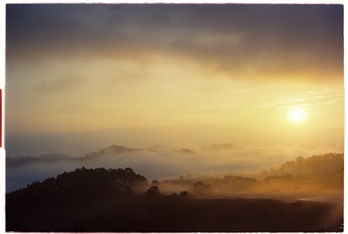 A sunrise over the foggy hills with a sun shining