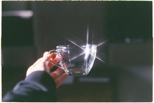A person holding a glass cup with a bright light