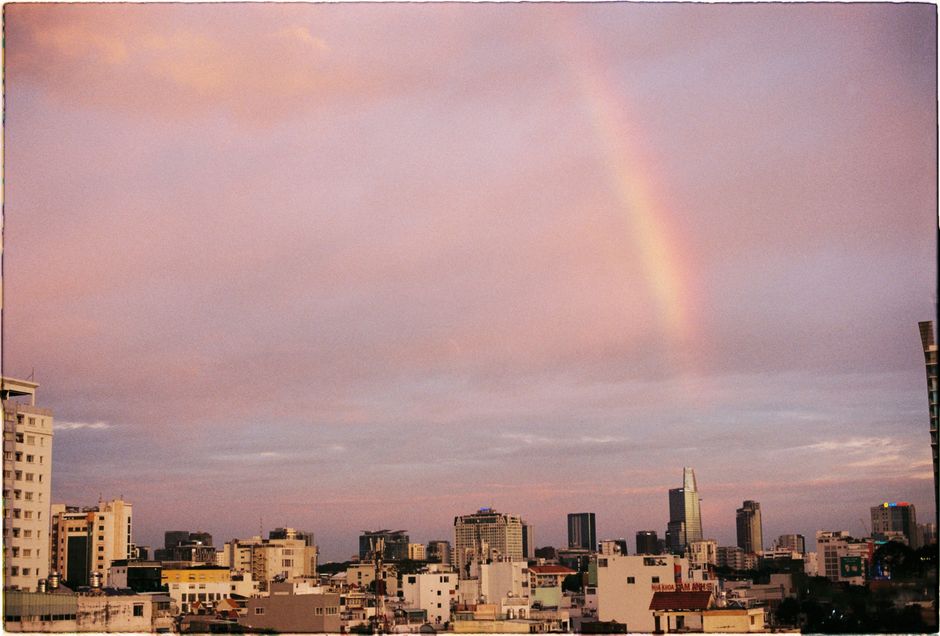 A stunning rainbow arches over a bustling city skyline during a serene dusk.