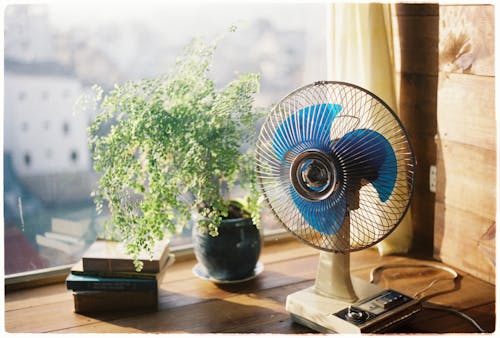 A fan on a table next to a window