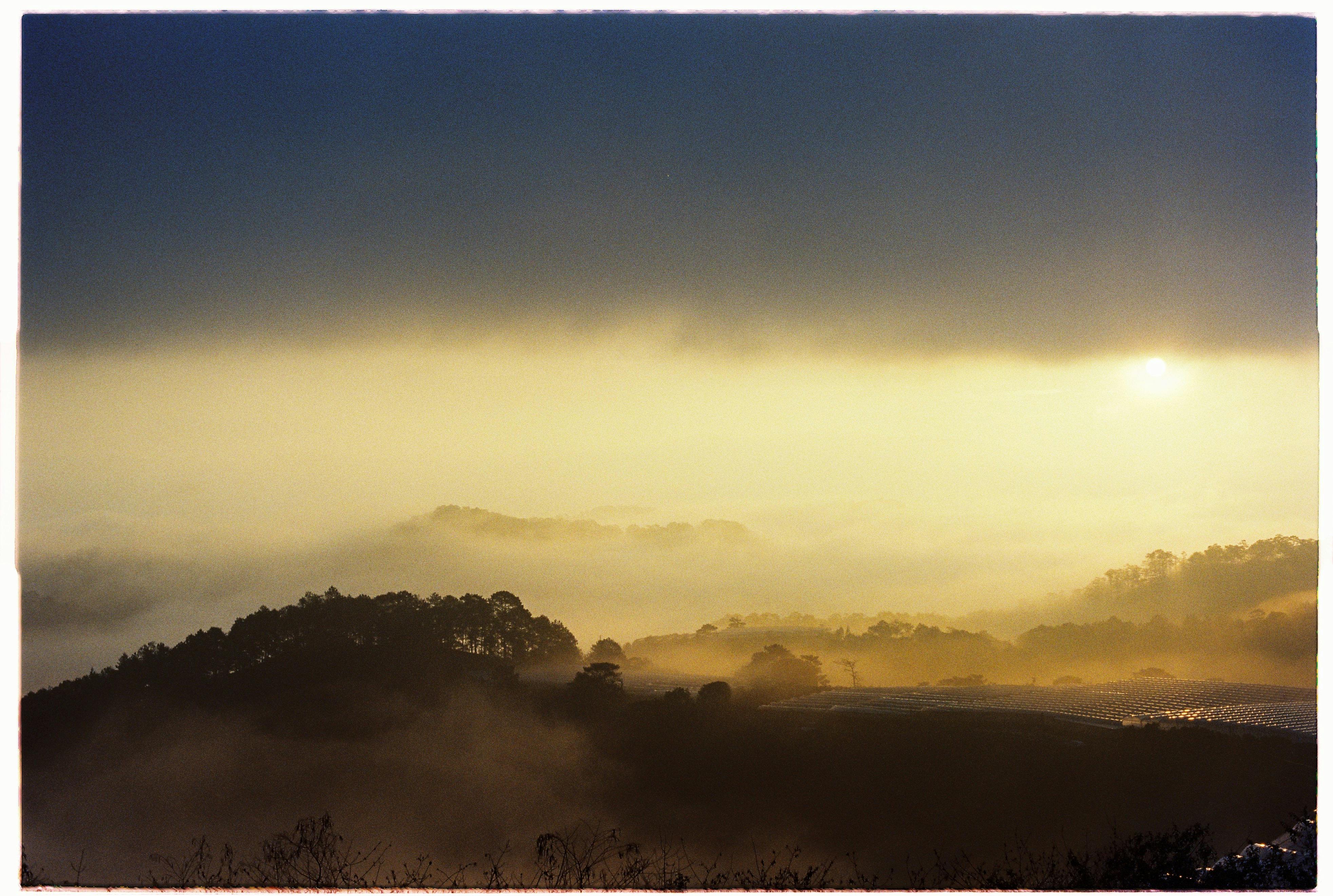 A breathtaking view of a misty landscape with hills silhouetted at sunset.