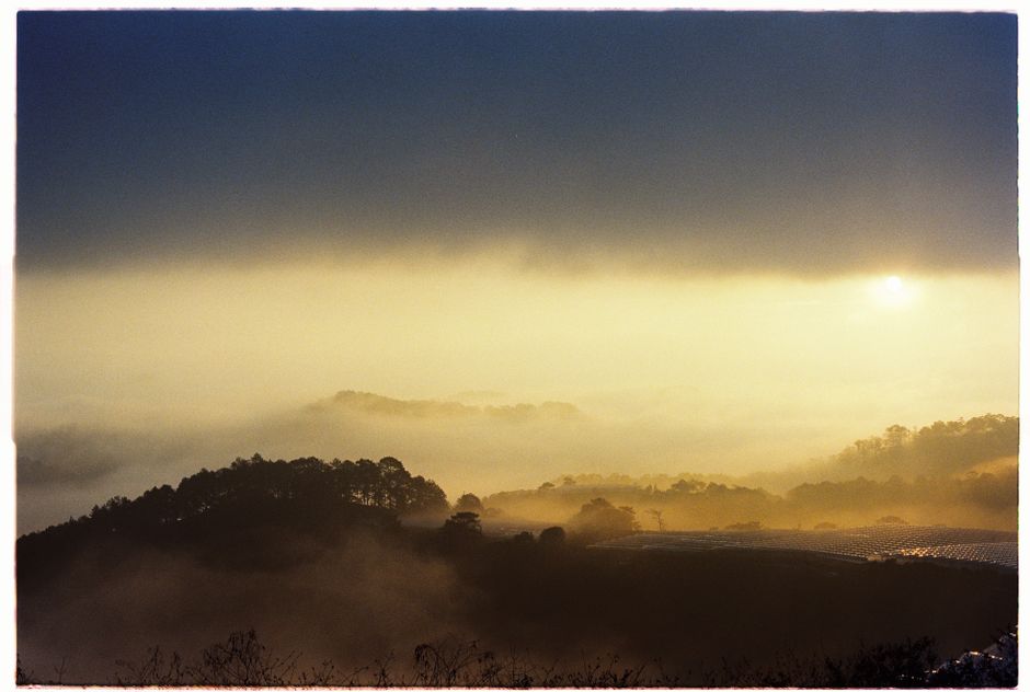 A breathtaking view of a misty landscape with hills silhouetted at sunset.