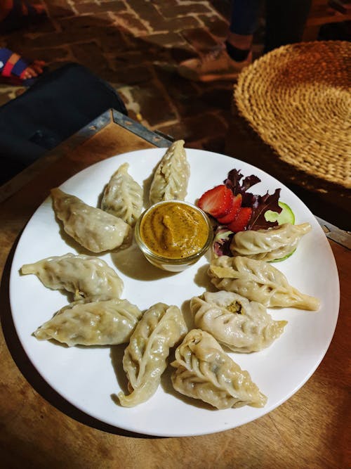 A plate of dumplings with sauce and a bowl of salad