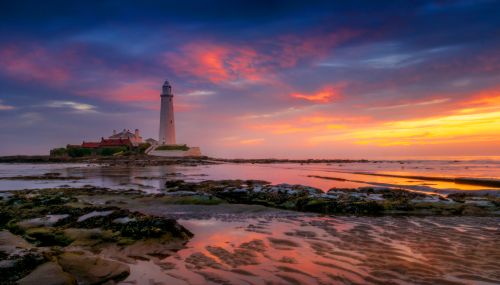 Free Beautiful sunset over St Mary's Lighthouse at Whitley Bay, UK, with vibrant sky and tranquil sea. Stock Photo