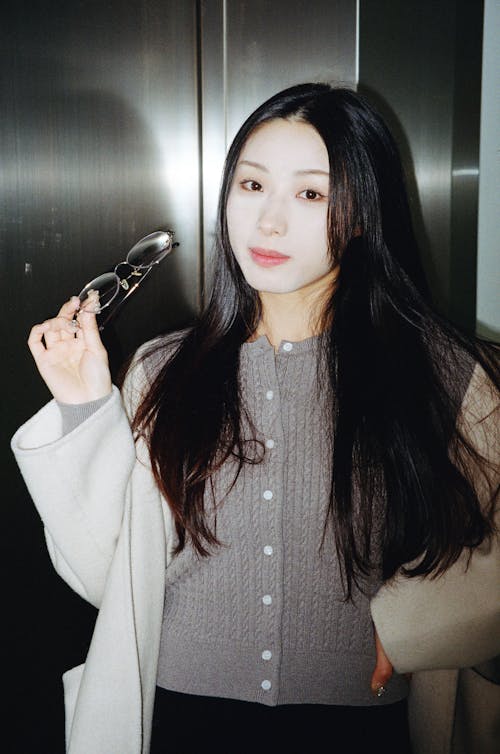 A woman with long hair and glasses holding a toothbrush