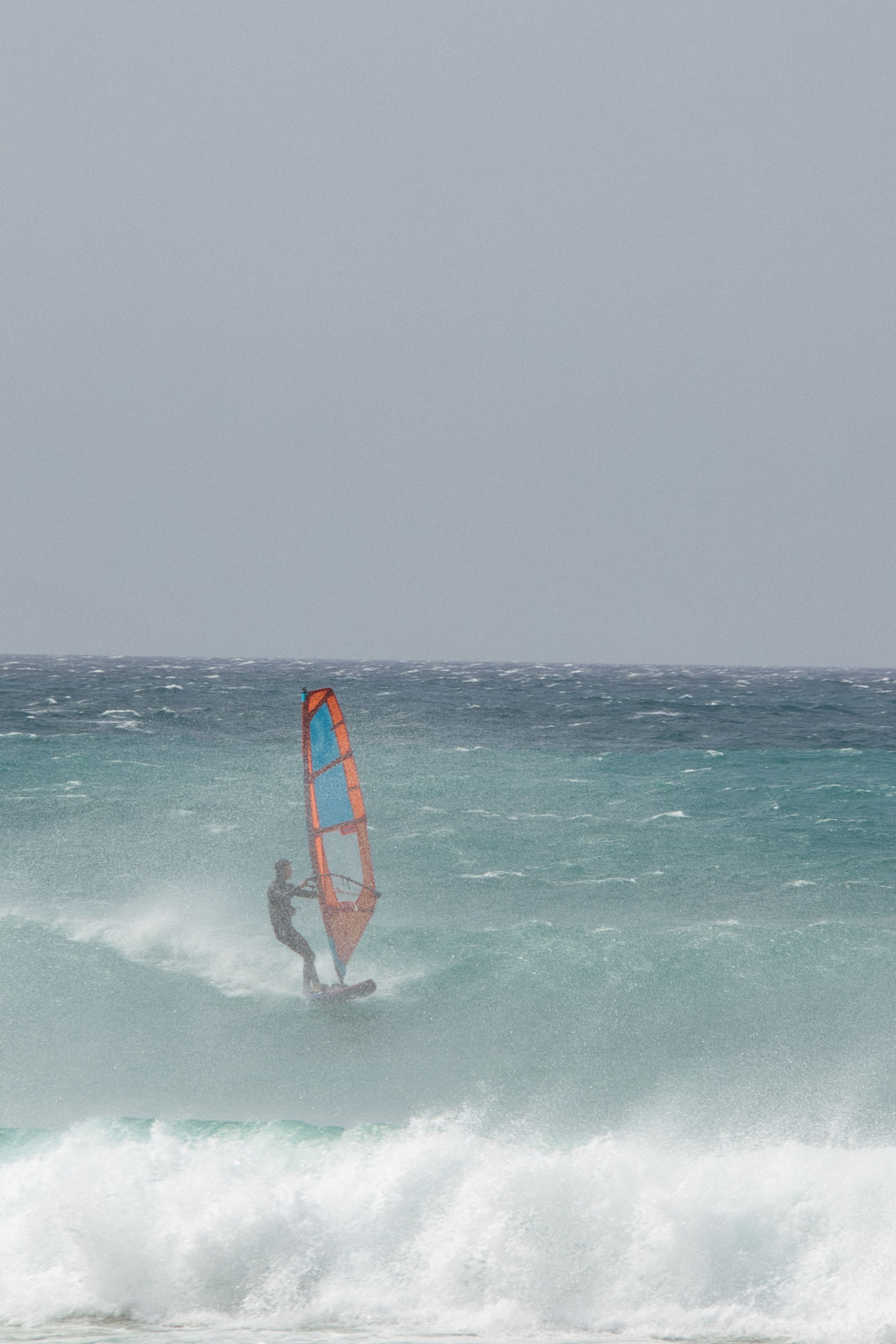 A skilled windsurfer rides the vibrant turquoise waves, capturing the essence of adventure and freedom.