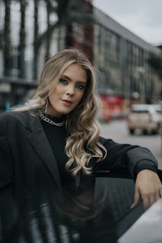 Elegant woman with long hair posing in city street, showcasing fashion and style.