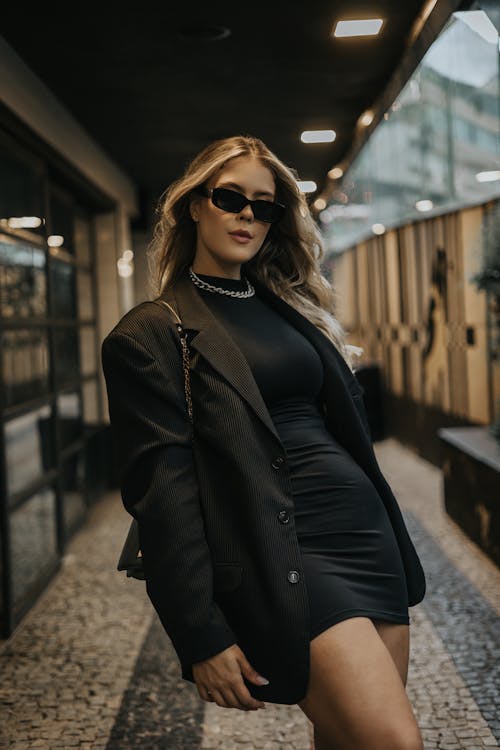 A woman in a black dress and sunglasses