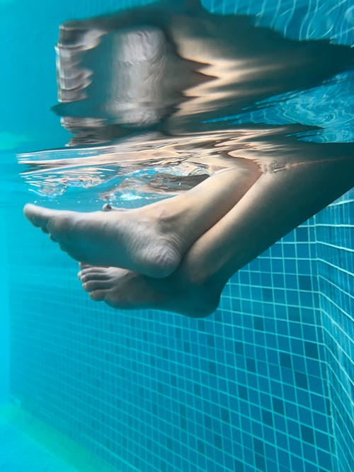 Person Holding Feet in Swimming Pool