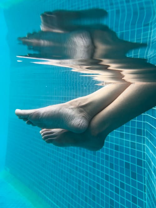 A woman's feet are in the water with a pool