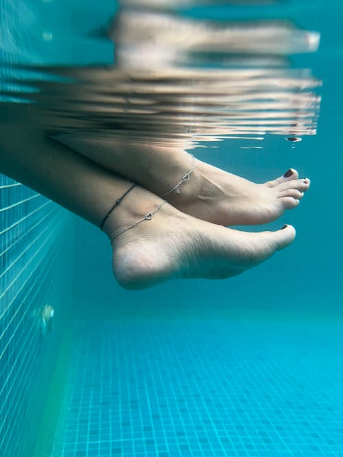 A person's feet are underwater with a tattoo on them