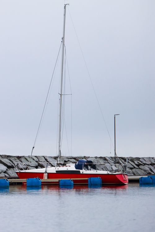 Free Red sailboat docked in Jönköping harbor, Sweden, showcasing nautical leisure. Stock Photo