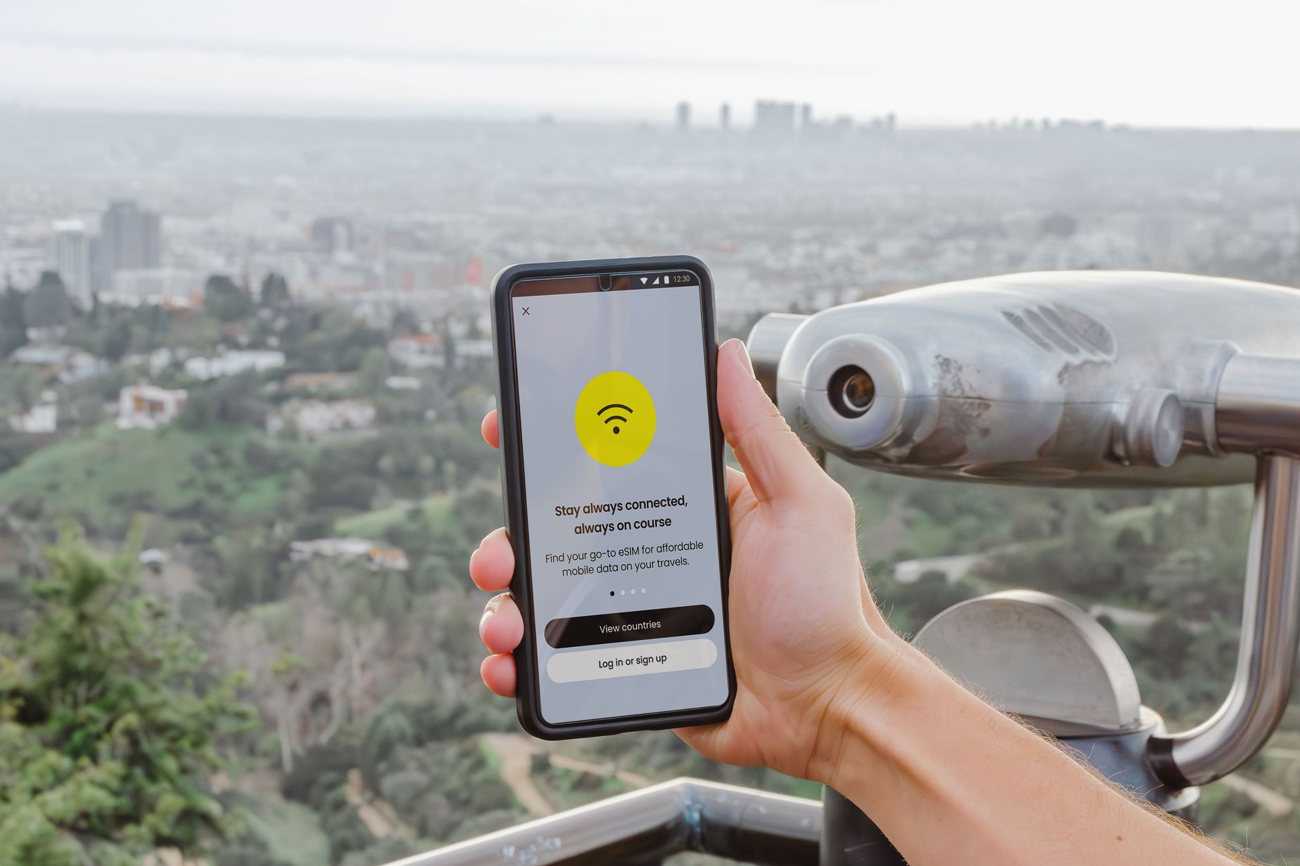 Smartphone displaying connectivity app with Los Angeles cityscape in the background.