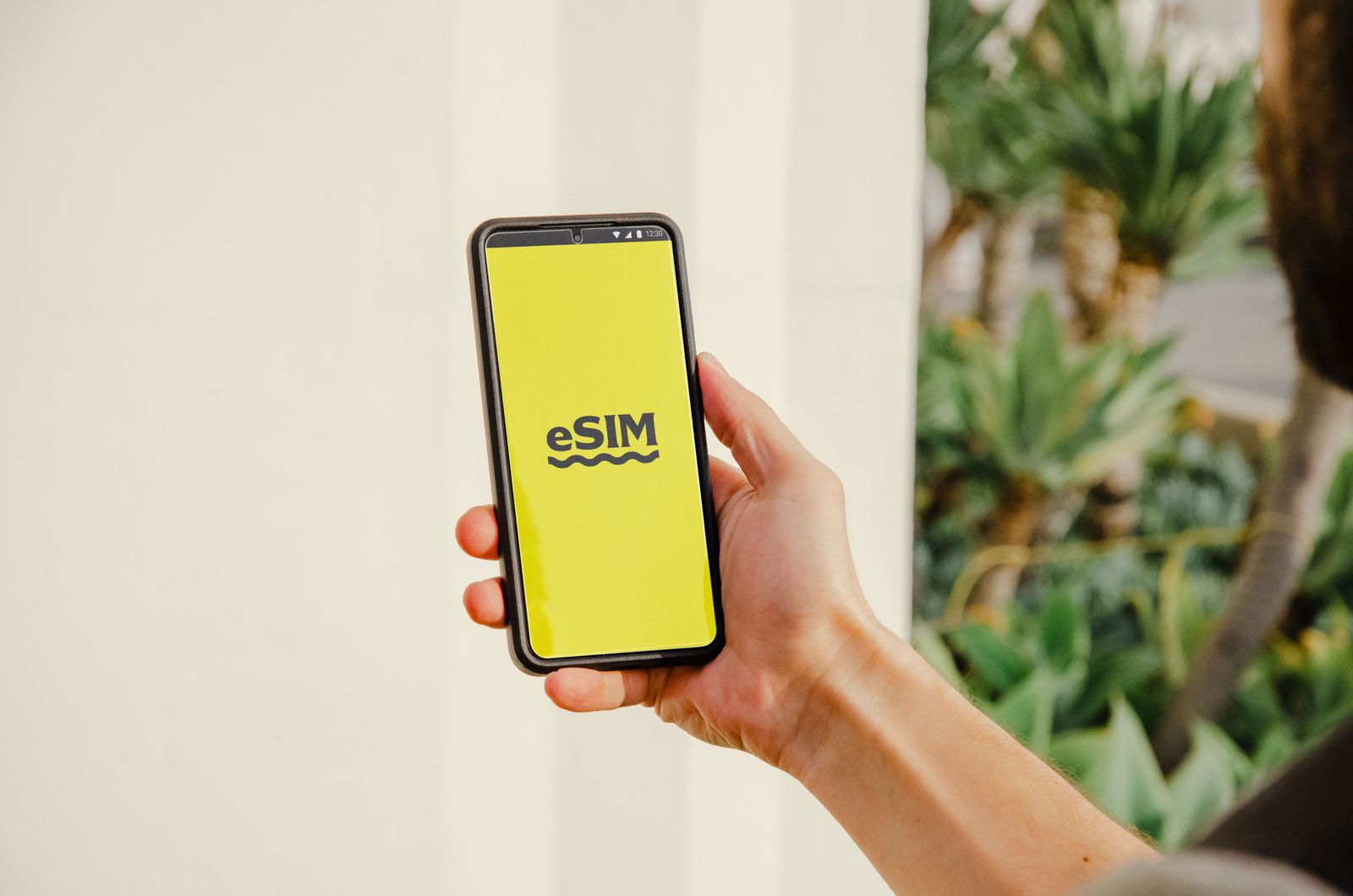 A person holds a smartphone with an eSIM logo outdoors, showcasing technology in Los Angeles.