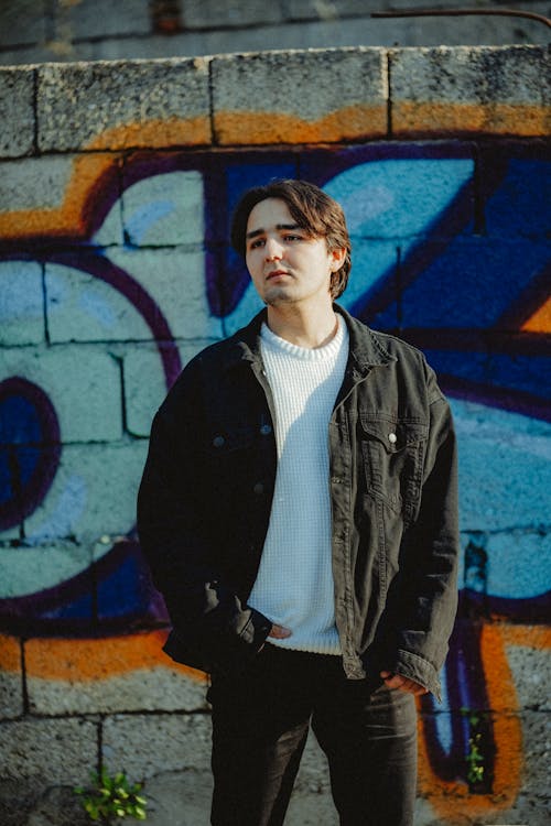 A man standing in front of a graffiti wall