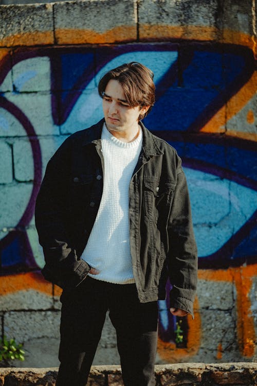 A man standing in front of a graffiti wall