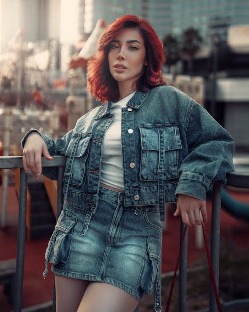 A woman with red hair posing in a denim jacket