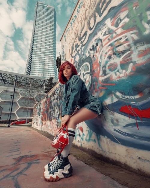 A woman in red shoes and jeans sitting on a wall