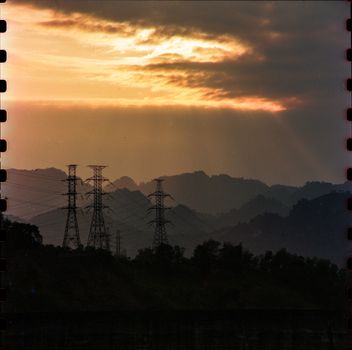 Dramatic sunset over mountains and power lines in Tuyên Quang, Vietnam, creating silhouettes with vibrant sky.