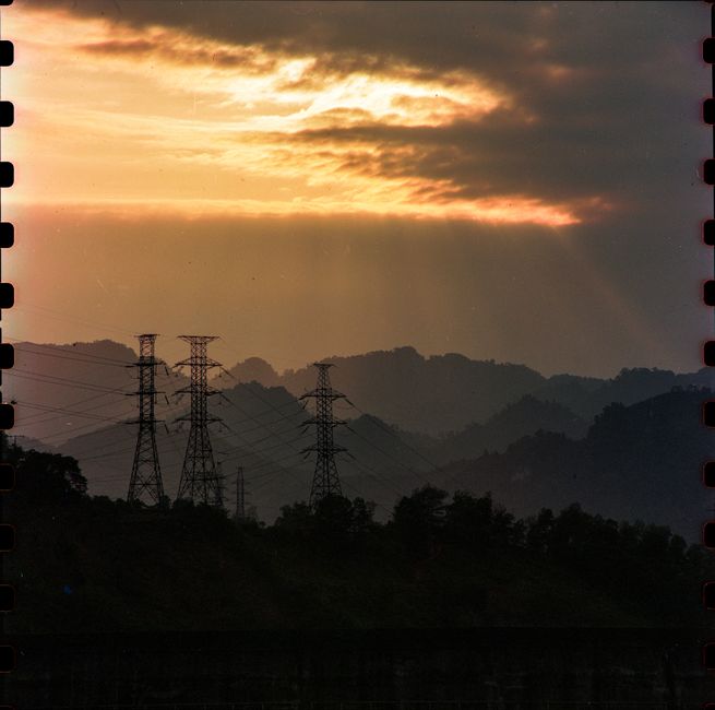 Dramatic sunset over mountains and power lines in Tuyên Quang, Vietnam, creating silhouettes with vibrant sky.