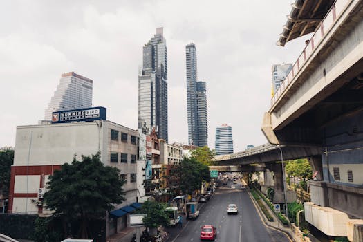 Urban scene in Bangkok showcasing skyscrapers, elevated road, and traffic in daylight.