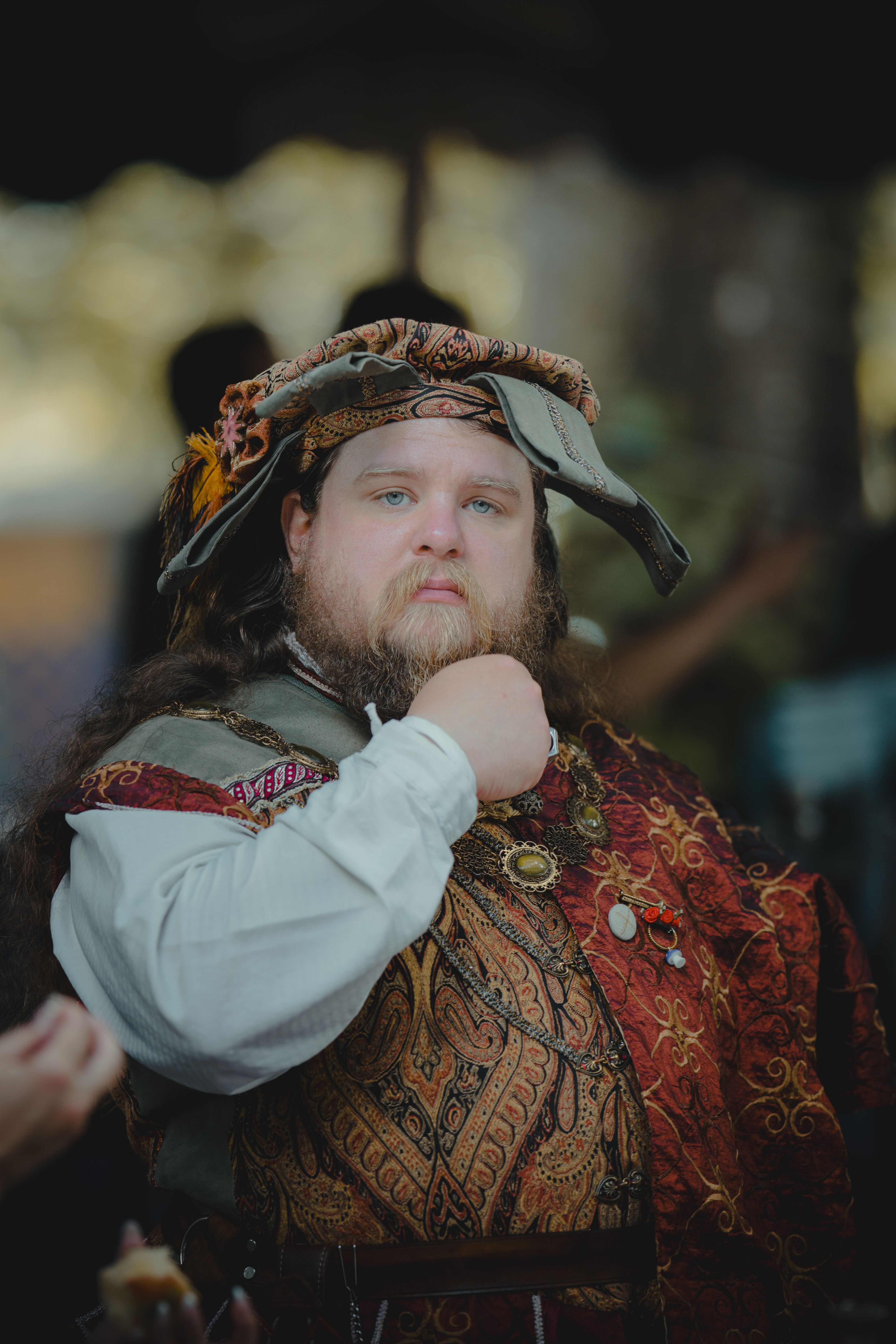 Renaissance fair attendee in traditional attire posing confidently outdoors.