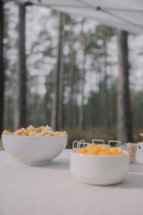 A table with bowls of popcorn and other snacks