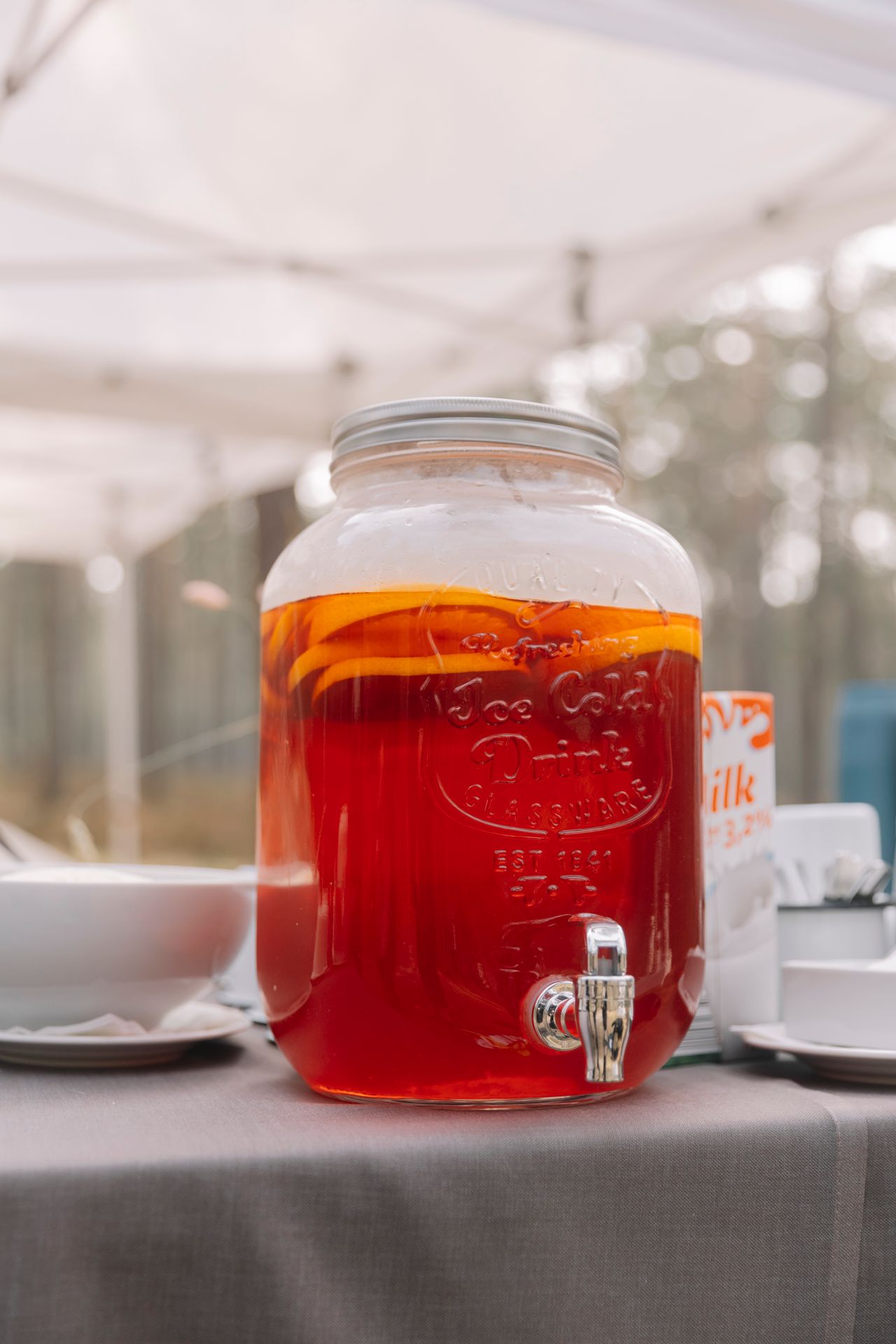 Glass drink dispenser filled with fall punch and citrus slices