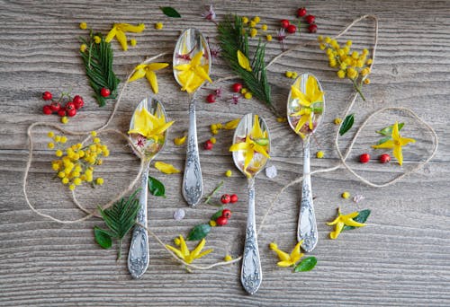 Spoons with flowers and leaves on a wooden table