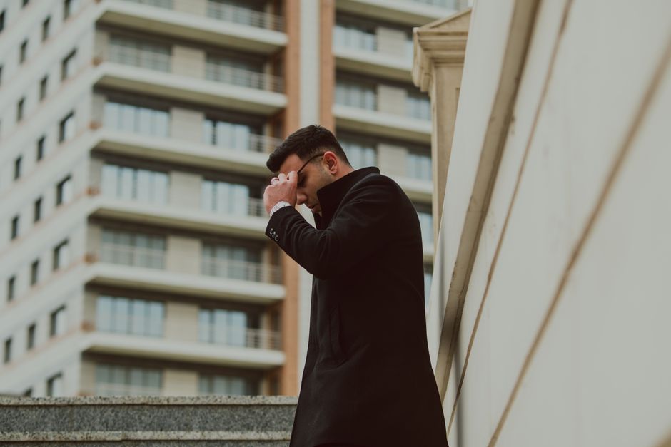 Elegant man in black coat standing in urban environment with modern buildings. Elegant man in black coat standing in urban environment with modern buildings.