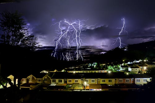 Lightning strikes over houses in the night sky