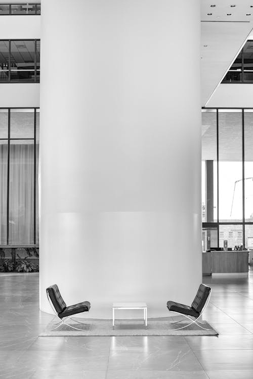 Black and white photo of two chairs in a large room