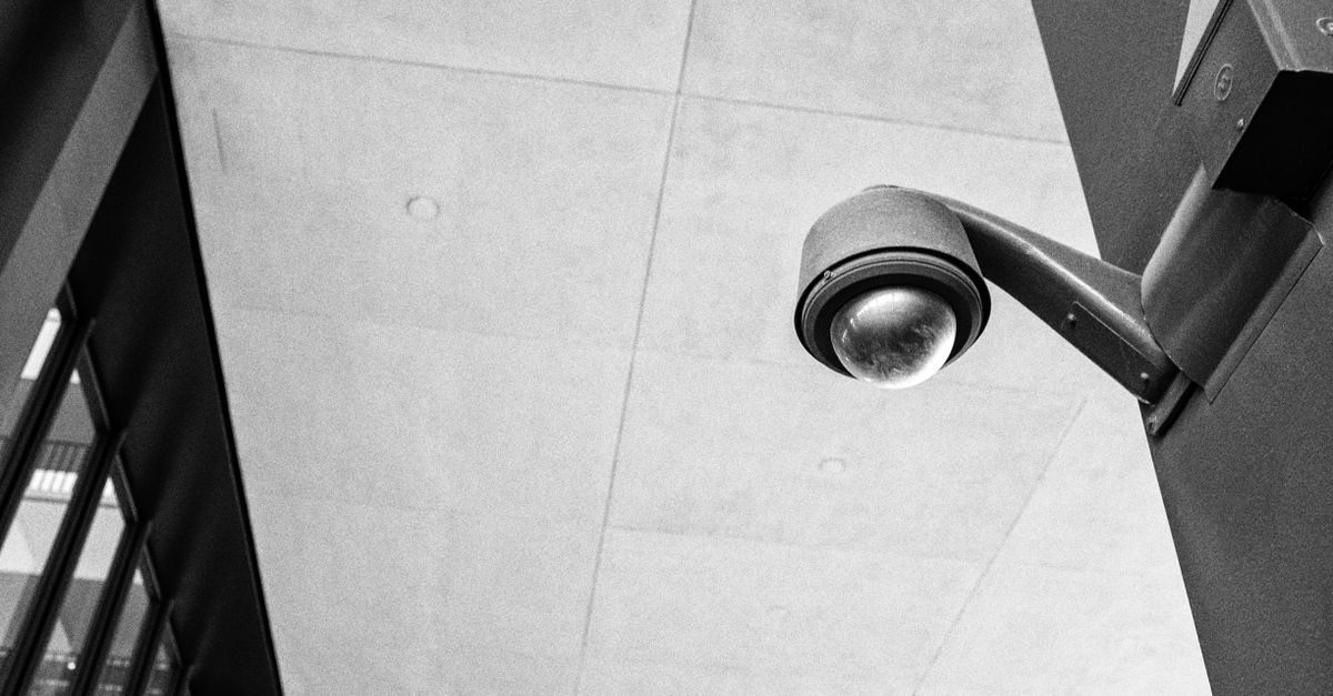 Monochrome image of a modern surveillance camera mounted outdoors, emphasizing security.