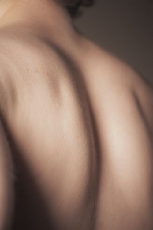 Free Elegant close-up of human back showing shoulder blades and soft shadows, emphasizing texture and form. Stock Photo