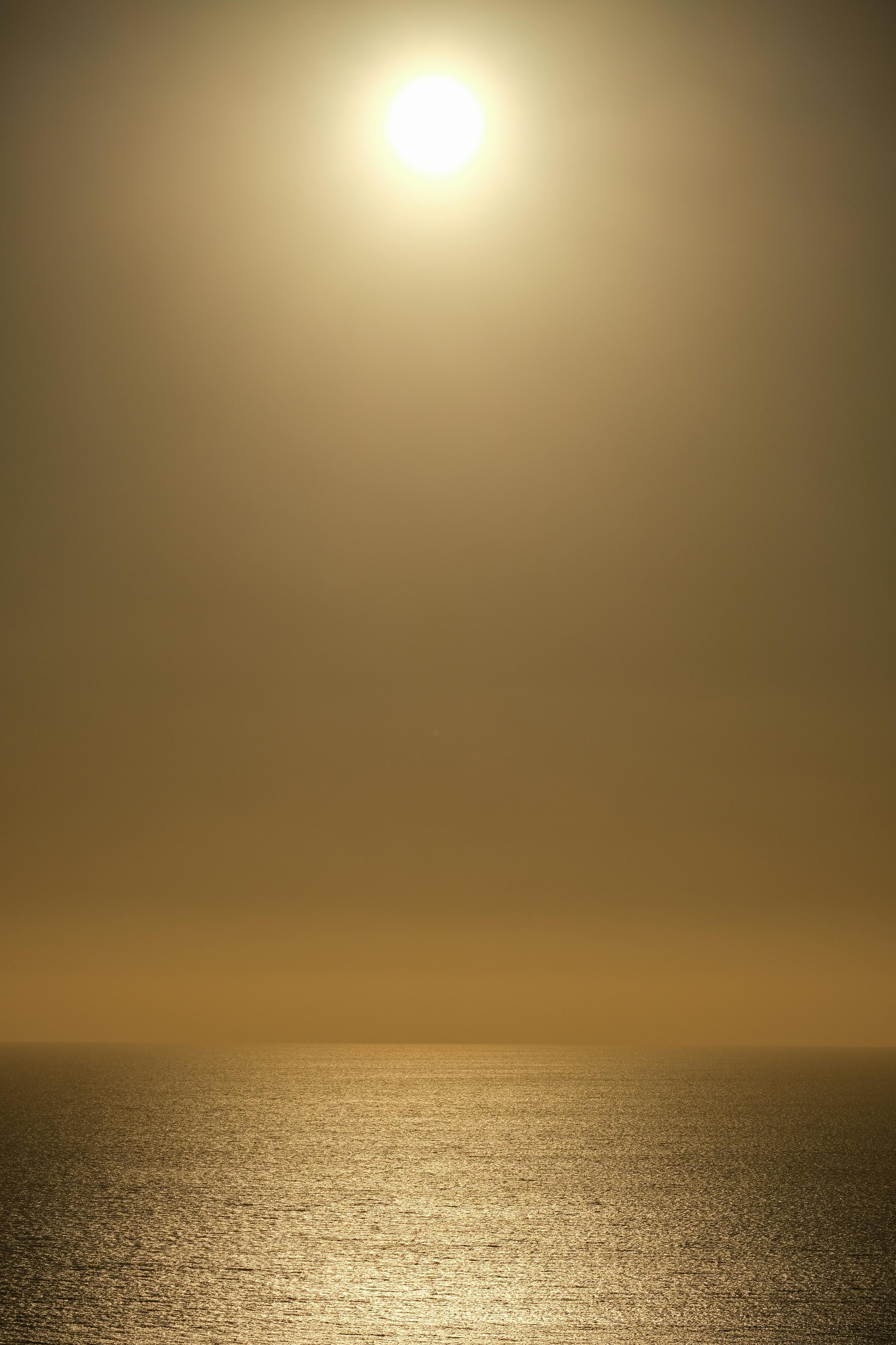 A tranquil sunset scene with a sun setting over a calm ocean, evoking peace.