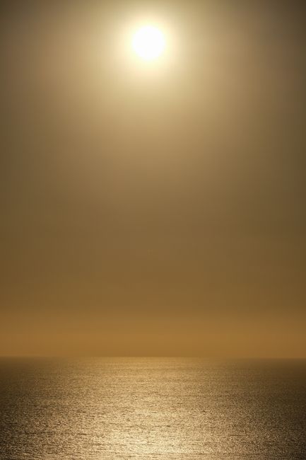A tranquil sunset scene with a sun setting over a calm ocean, evoking peace.