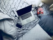 卧室里很舒适，床上放着一台笔记本电脑和一本书，枕头柔软